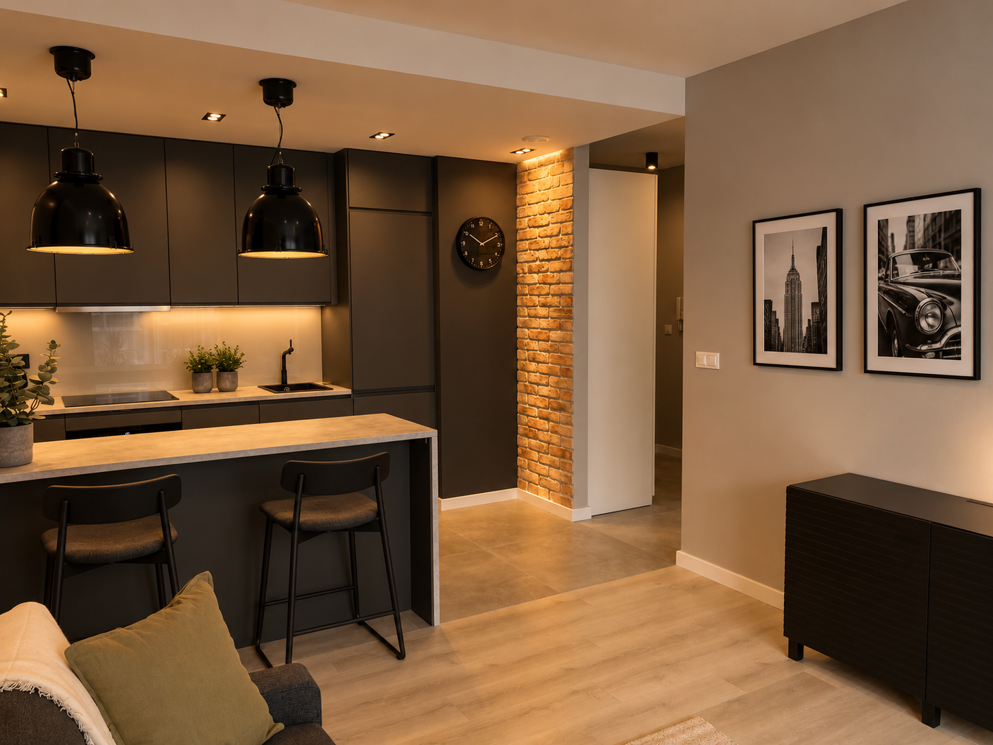 Kawalerka w stylu loft z ciemną kuchnią i ścianą z cegły – projekt Simply Concept